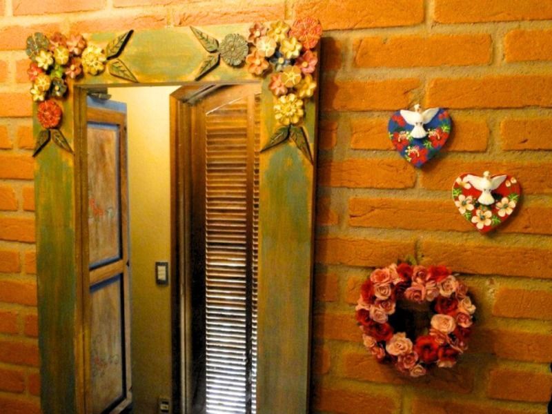 Espelho decorado em parede de tijolos com detalhes florais e ornamentos em forma de coração.