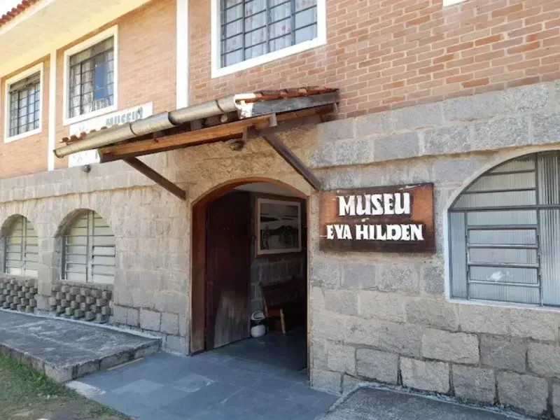 Entrada do Museu Eva Hilden, com fachada de tijolos e pedra e porta de madeira sob um toldo.