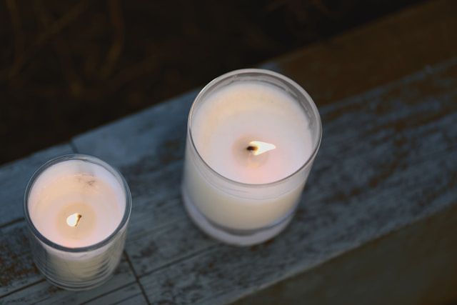 Two lit candles in glass holders on rustic surface, symbolizing remembrance, cremation services Fulton, IL