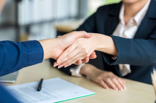A man in a suit and tie with two other people shaking their hands A man in a suit and tie with two other people shaking their hands