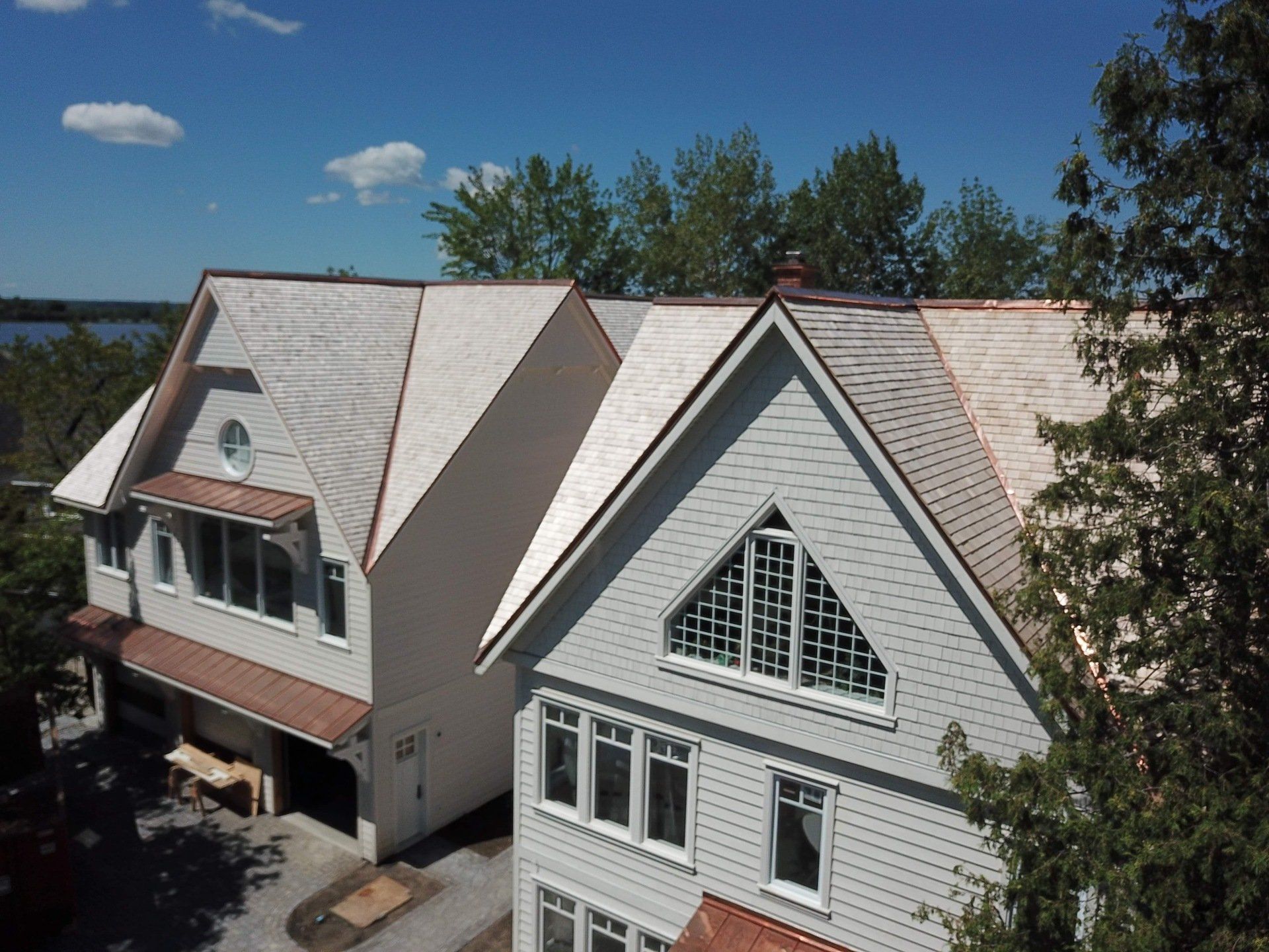 Two white houses with shingled roofs sit beside a body of water under a clear blue sky.