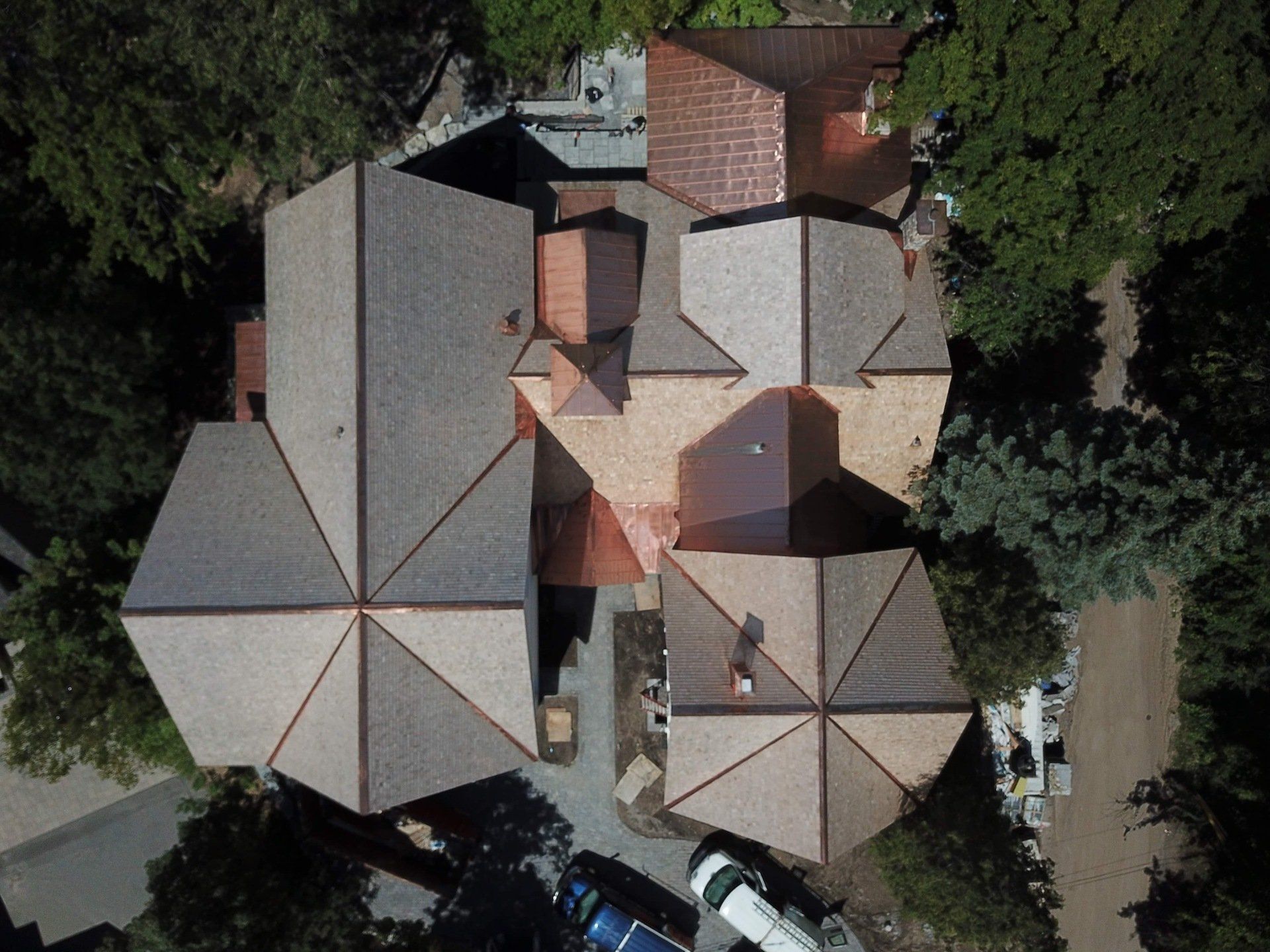 Top-down aerial view of a house with a complex, multi-gabled roof featuring gray shingles and copper flashing accents.