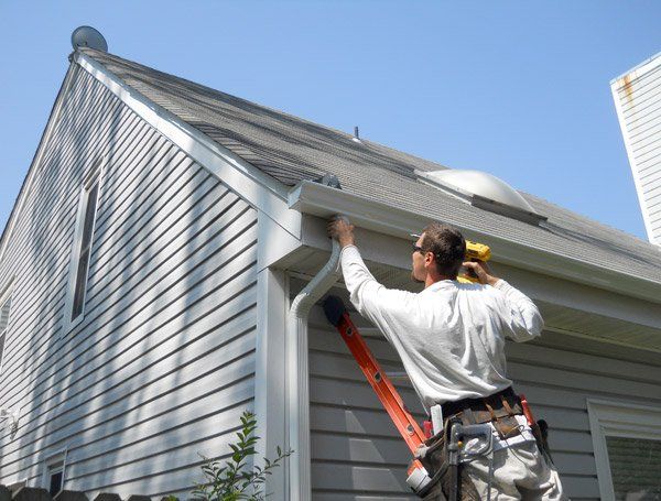A man on a ladder is working on the side of a house.