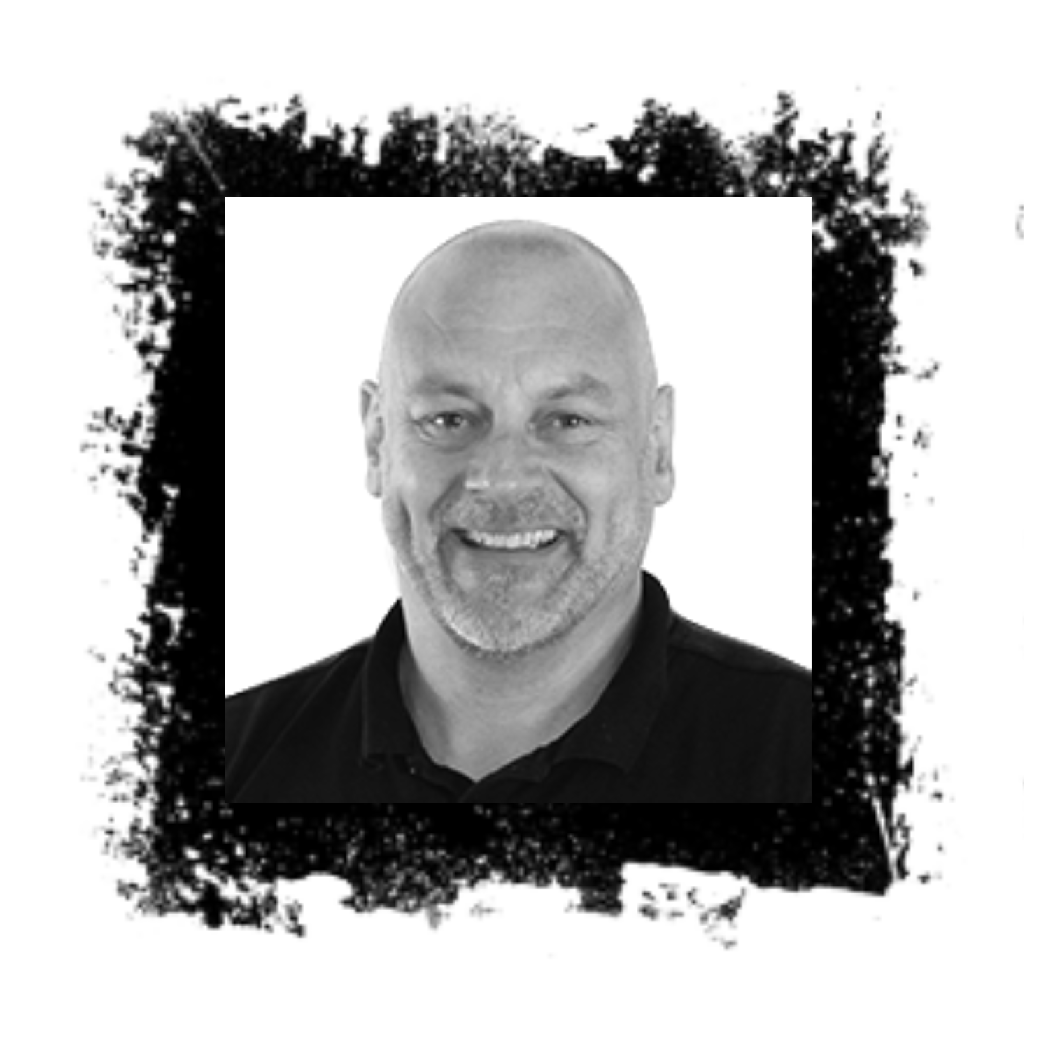 Bald man with a beard smiles in a black and white headshot, framed by a rough-edged black border.