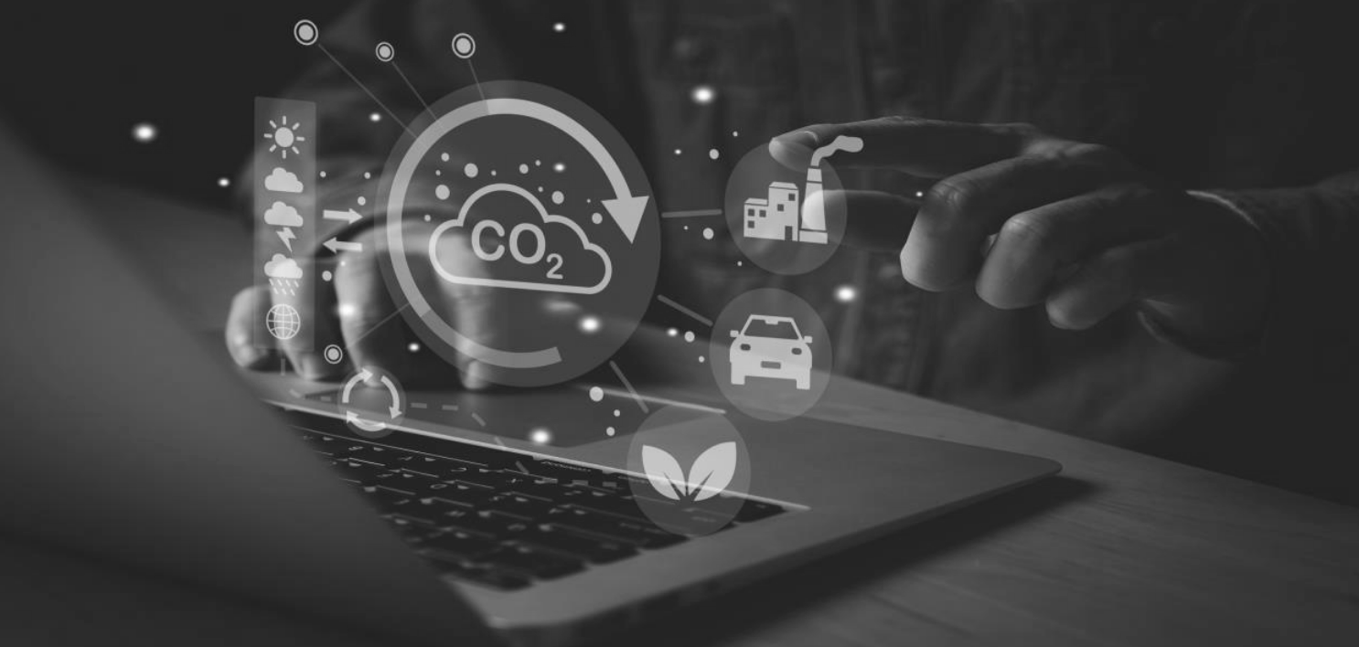 A person using a laptop with icons representing CO2 emissions and the environment overlaid, suggesting efforts towards climate change.