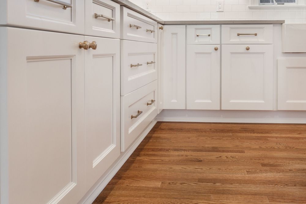 A Kitchen with White Cabinets and Wooden Floors — Rodney Lees Cabinetmaking In Byron Bay, NSW