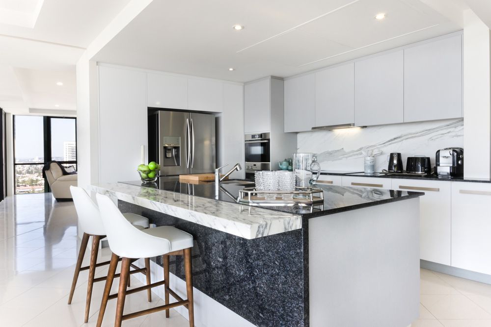 A Kitchen with White Cabinets, Black Counter Tops, Stools and A Large Island — Rodney Lees Cabinetmaking In Byron Bay, NSW