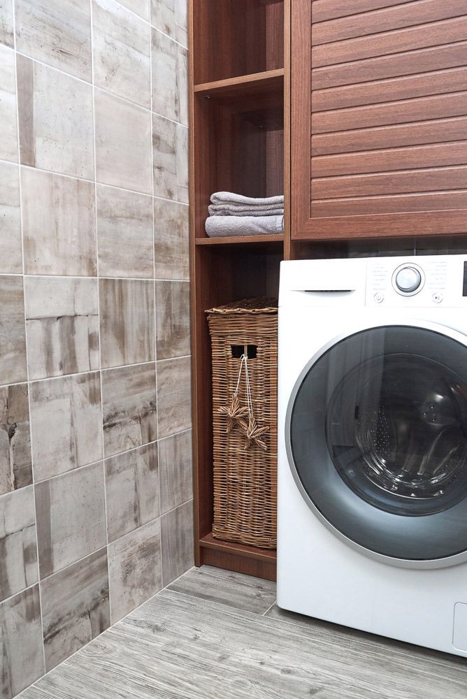 A Washing Machine Is Sitting in A Laundry Room Next to A Wicker Basket — Rodney Lees Cabinetmaking In Ballina, NSW