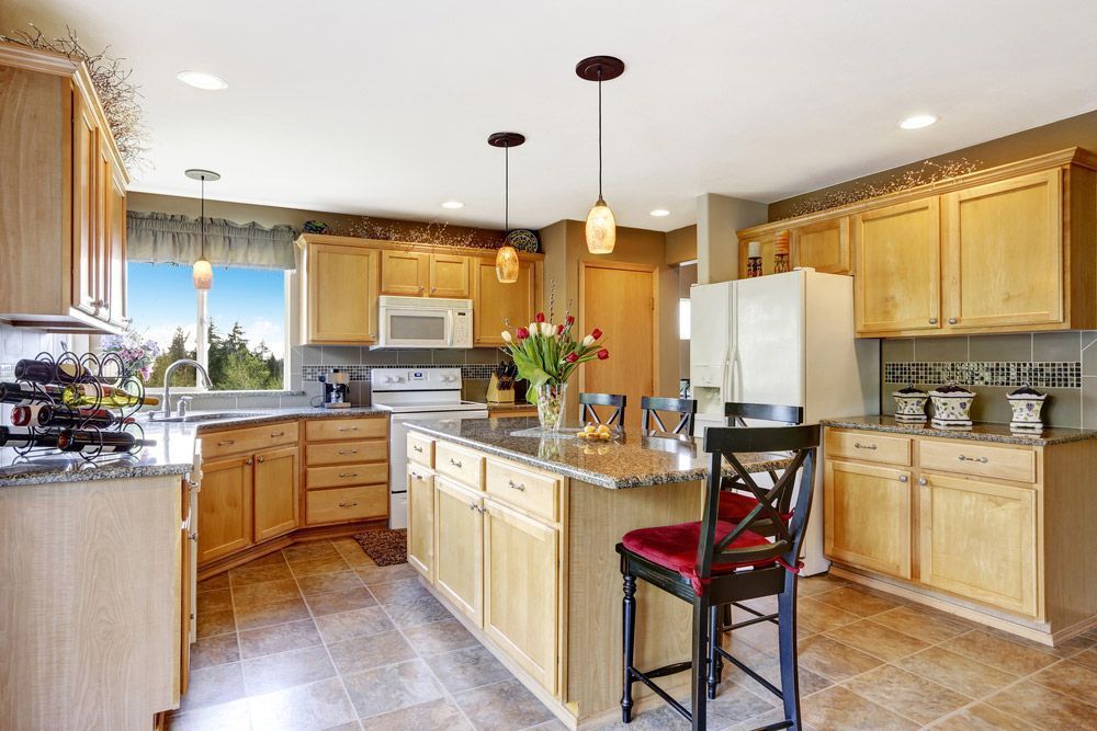 A Kitchen with Wooden Cabinets, Granite Counter Tops, and A Large Island — Rodney Lees Cabinetmaking In Ballina, NSW