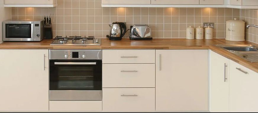 A Kitchen with White Cabinets and Stainless Steel Appliances — Rodney Lees Cabinetmaking In Ballina, NSW