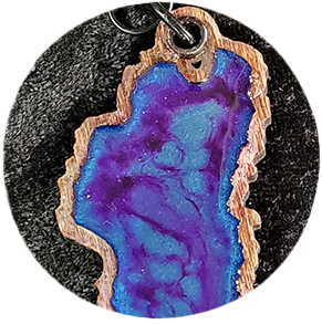 Wooden keychain with blue and purple resin inlay, a silver ring, and a dark speckled background.