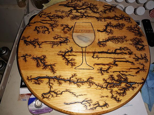 Round wooden board with Lichtenberg figure design. A wine glass shape is in the center.