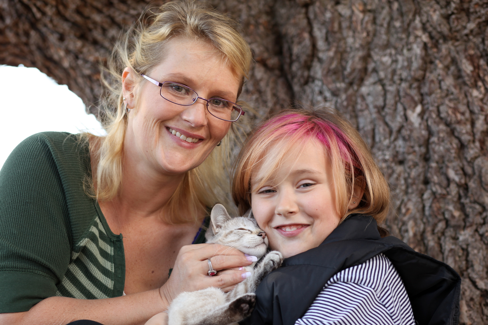Happy family. No stress, no worriesA woman and a girl are holding a kitten under a tree.
