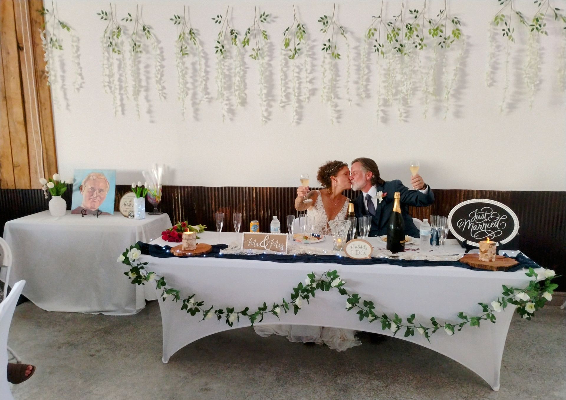 Decorated head table at a wedding reception with floral garlands and seated guests