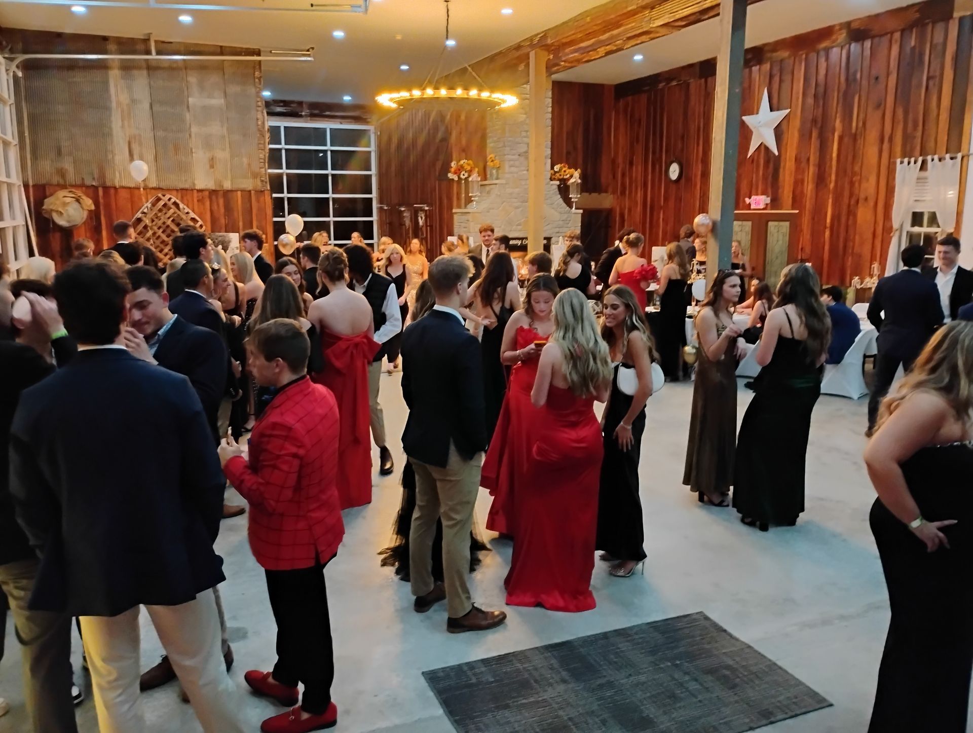 People mingling and dancing at a crowded indoor party with warm lighting and wood-paneled walls