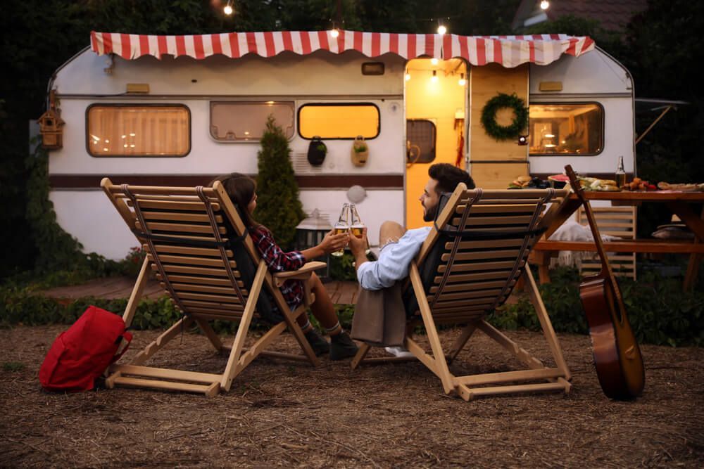 A Man And A Woman Are Sitting In Lawn Chairs In Front Of A Trailer — Affordable Caravan Repairs in Bundaberg, QLD