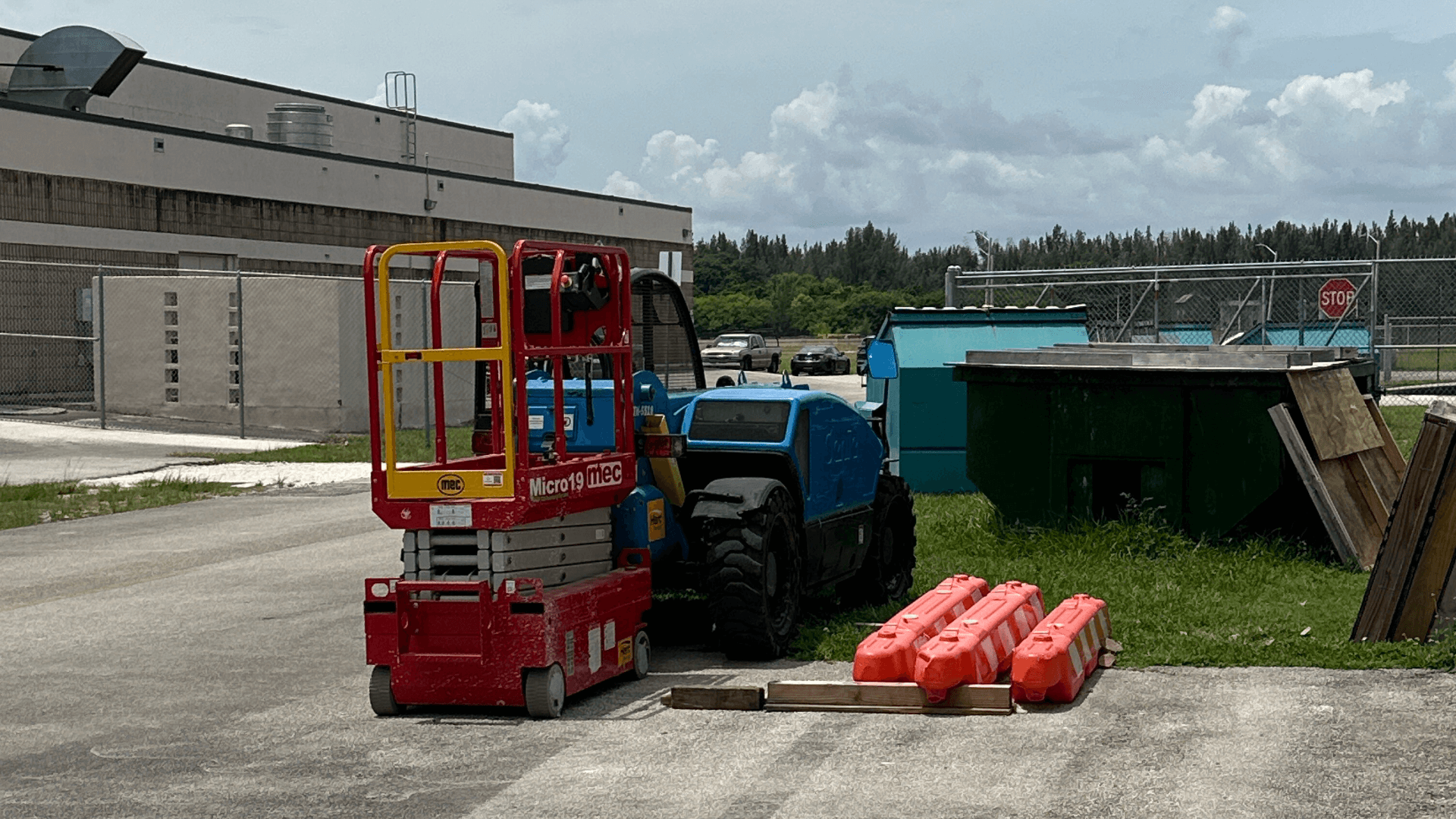 A red and yellow scissor lift is parked in front of a building.