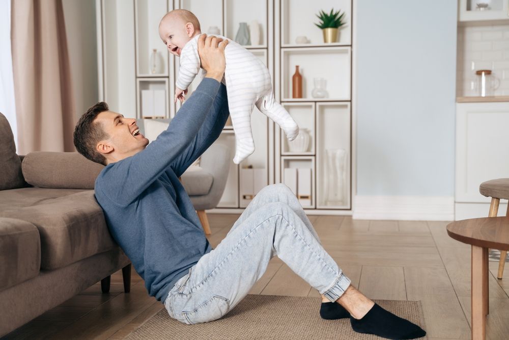 A man is sitting on the floor holding a baby in his arms.