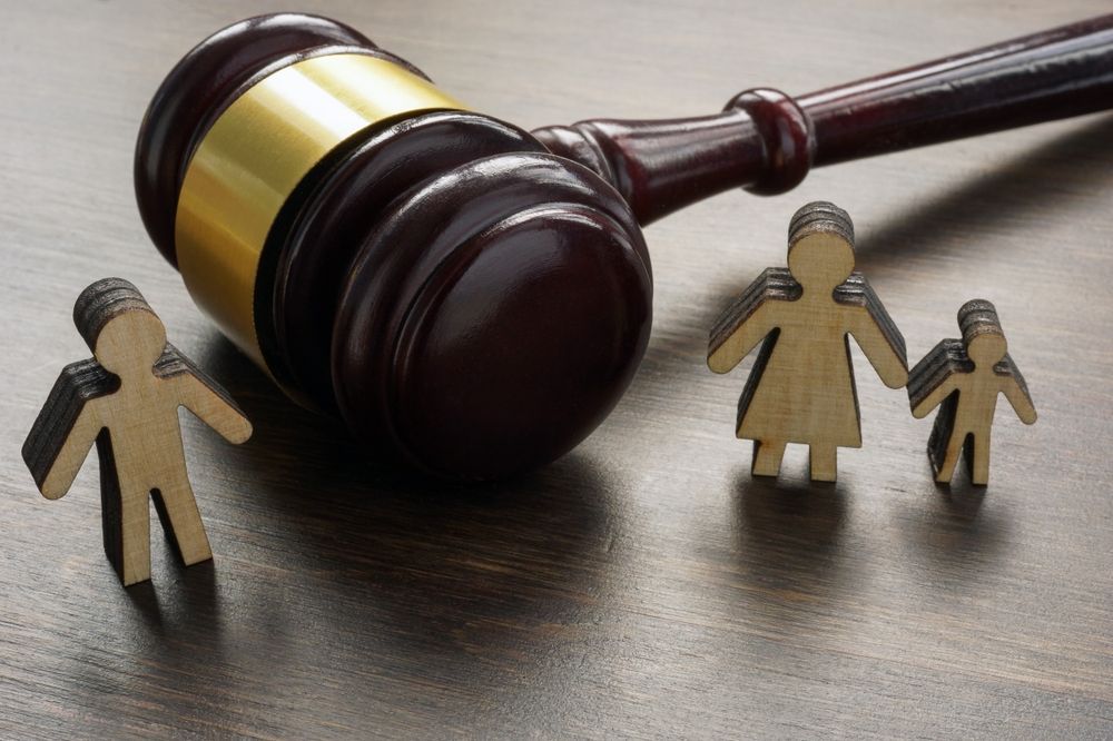 A wooden family is standing next to a wooden gavel on a wooden table.