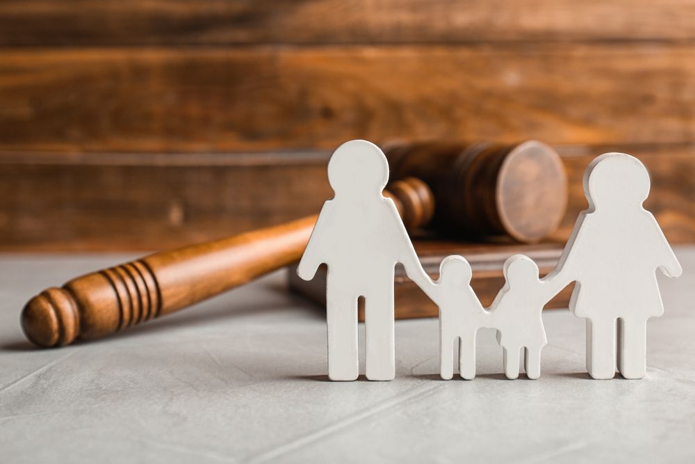 A group of people are sitting at a table with scales of justice and a judge 's gavel.