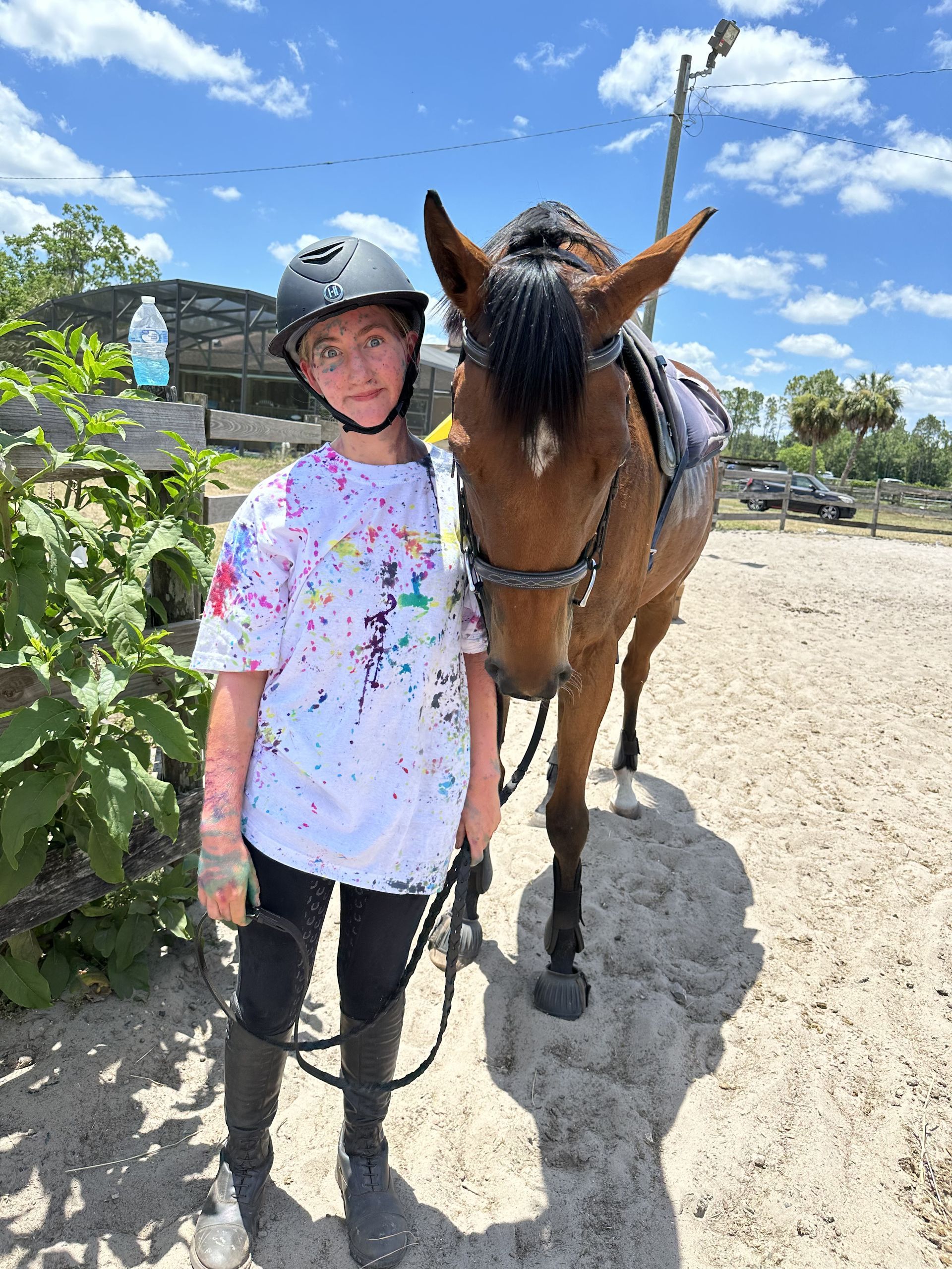 A young girl is standing next to a brown horse.