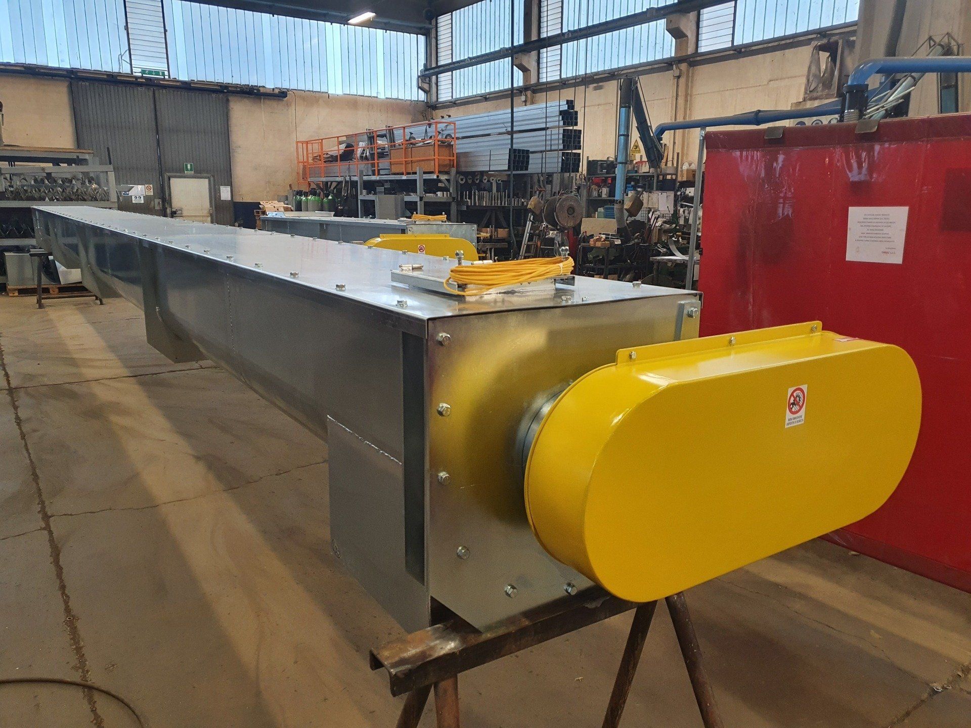 Un nastro trasportatore con un motore giallo è appoggiato su un tavolo in una fabbrica.