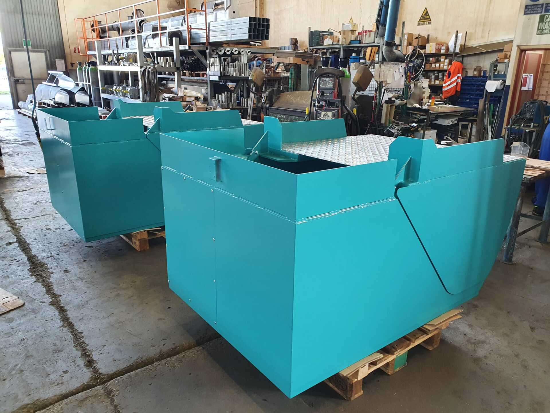 Due container blu sono appoggiati su un pallet di legno in una fabbrica.
