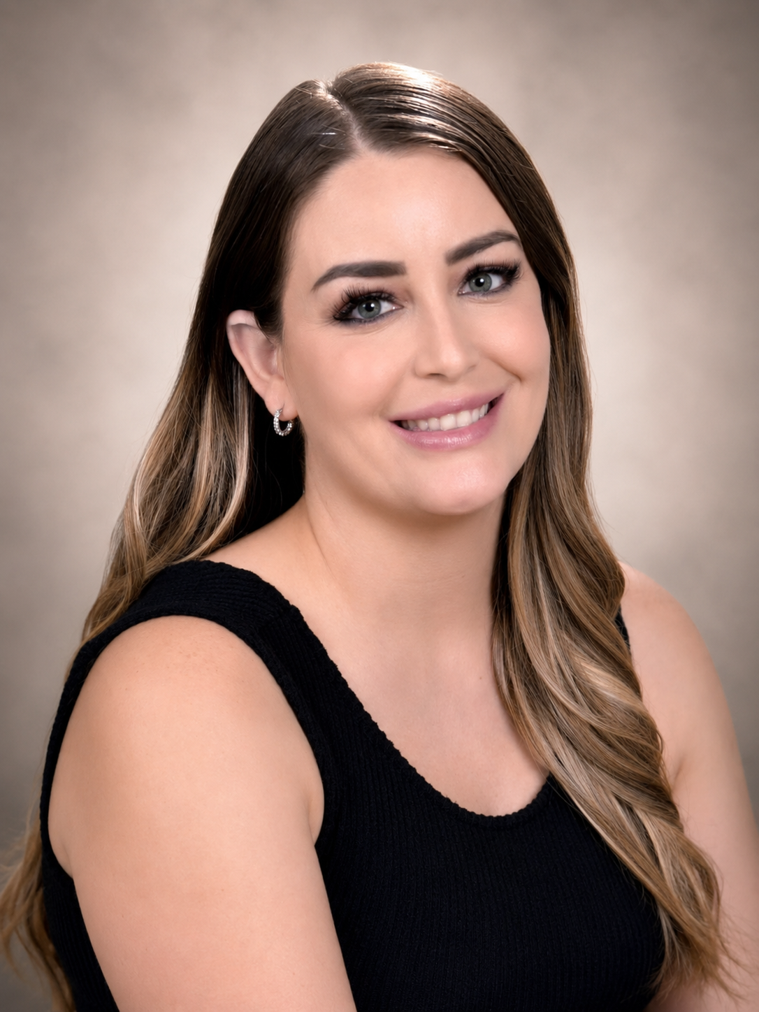 Portrait of a smiling woman in a black sleeveless top against a soft gray background