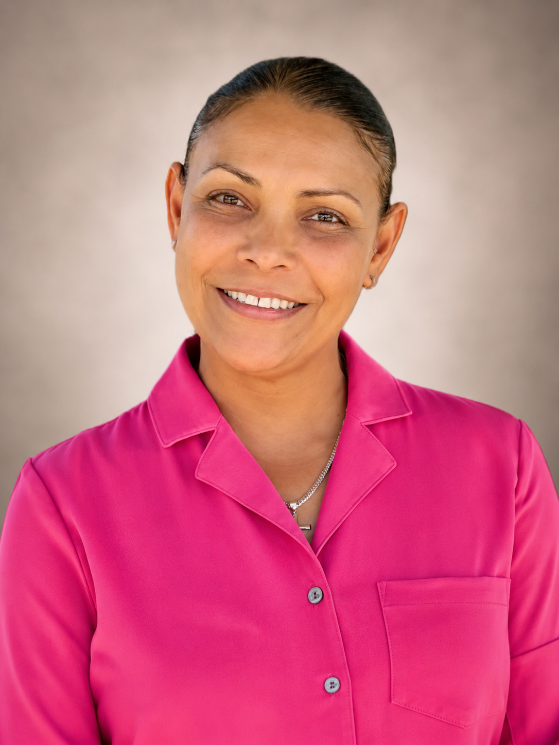 Smiling person in a bright pink collared shirt against a neutral background