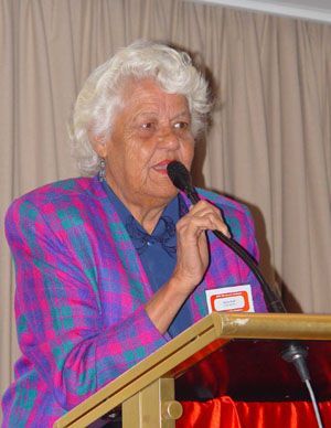 A woman is standing at a podium speaking into a microphone.