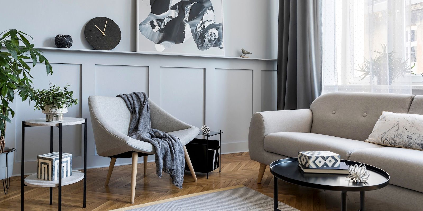 Living room with gray walls, furniture, and decor. Includes a plant, clock, and artwork.