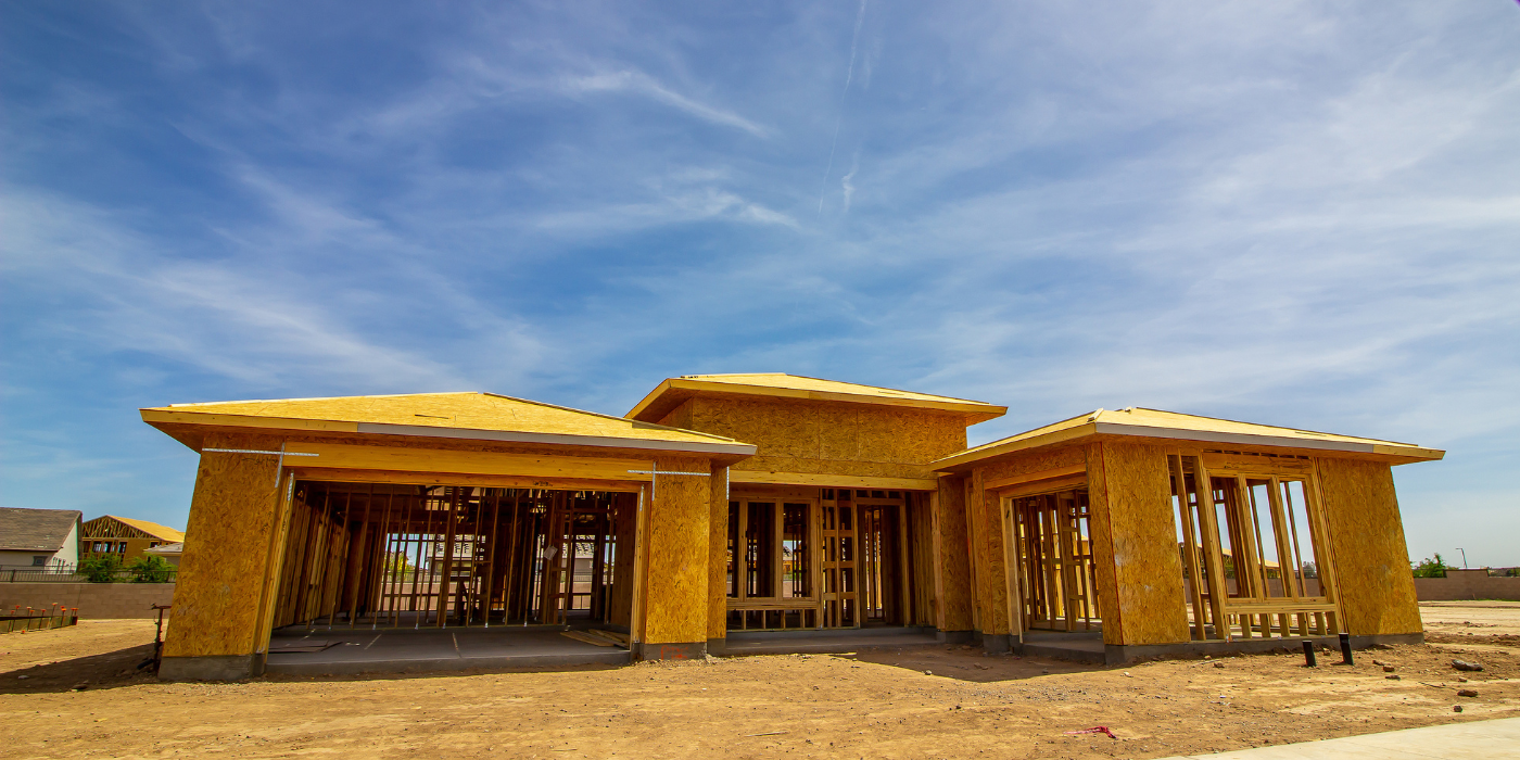 House frame under construction on a sunny day with blue sky.