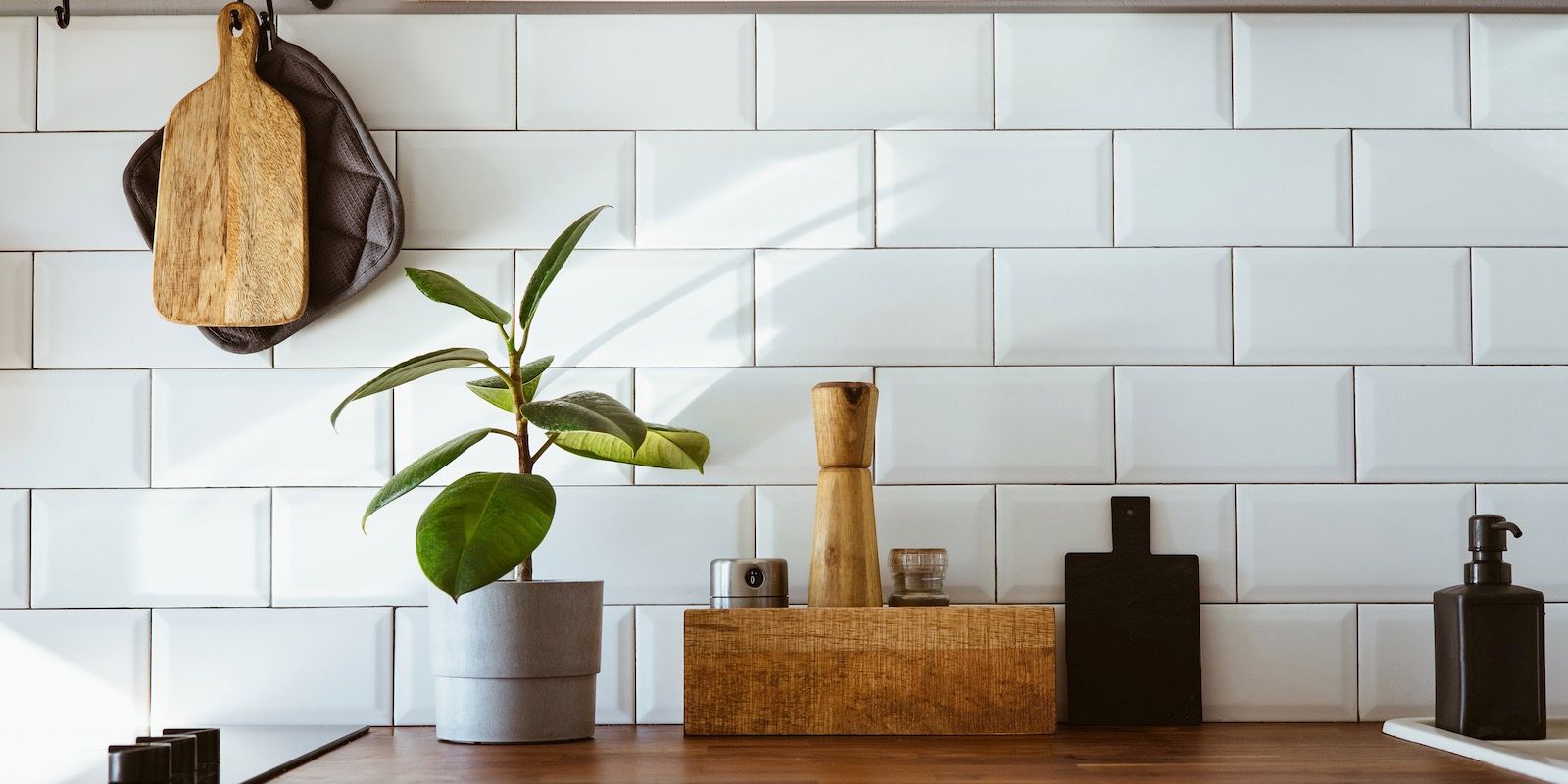 Kitchen counter with potted plant, cutting boards, and white subway tile backsplash.