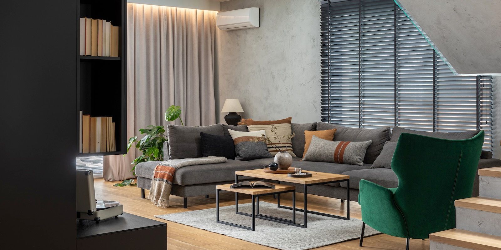 Living room with gray sectional, wooden coffee tables, green chair, and bookshelf.