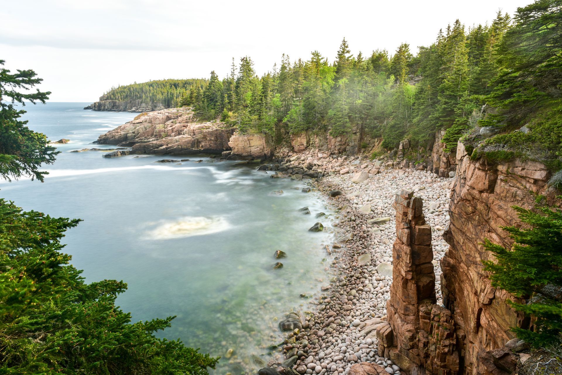 A view of a cliff overlooking a body of water surrounded by trees.