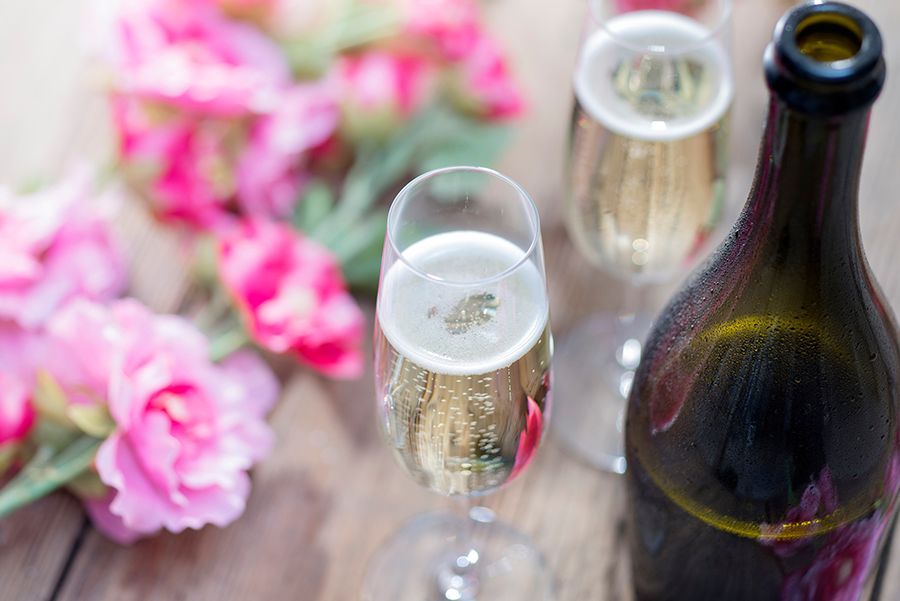 Two glasses of champagne and a bottle of champagne on a wooden table.