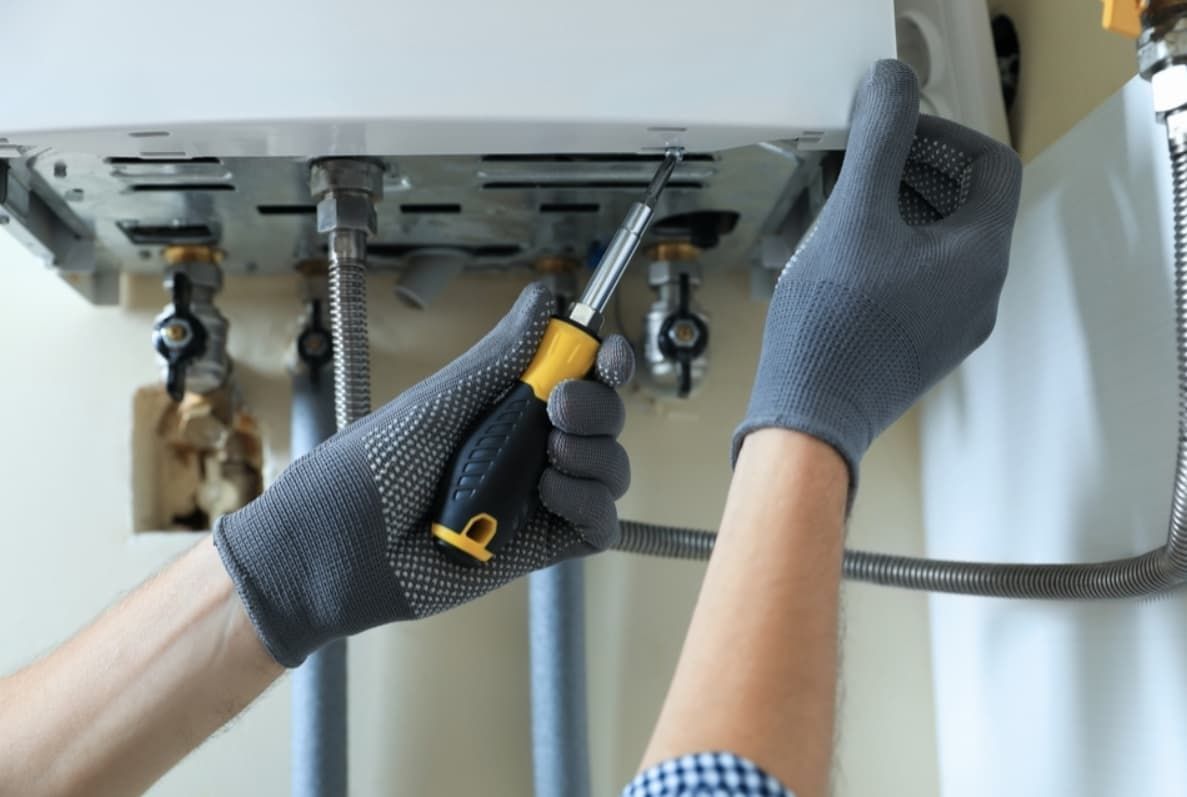 A Person Is Fixing A Water Heater With A Screwdriver — Mozzlec Electrical & Airconditioning In Urangan, QLD