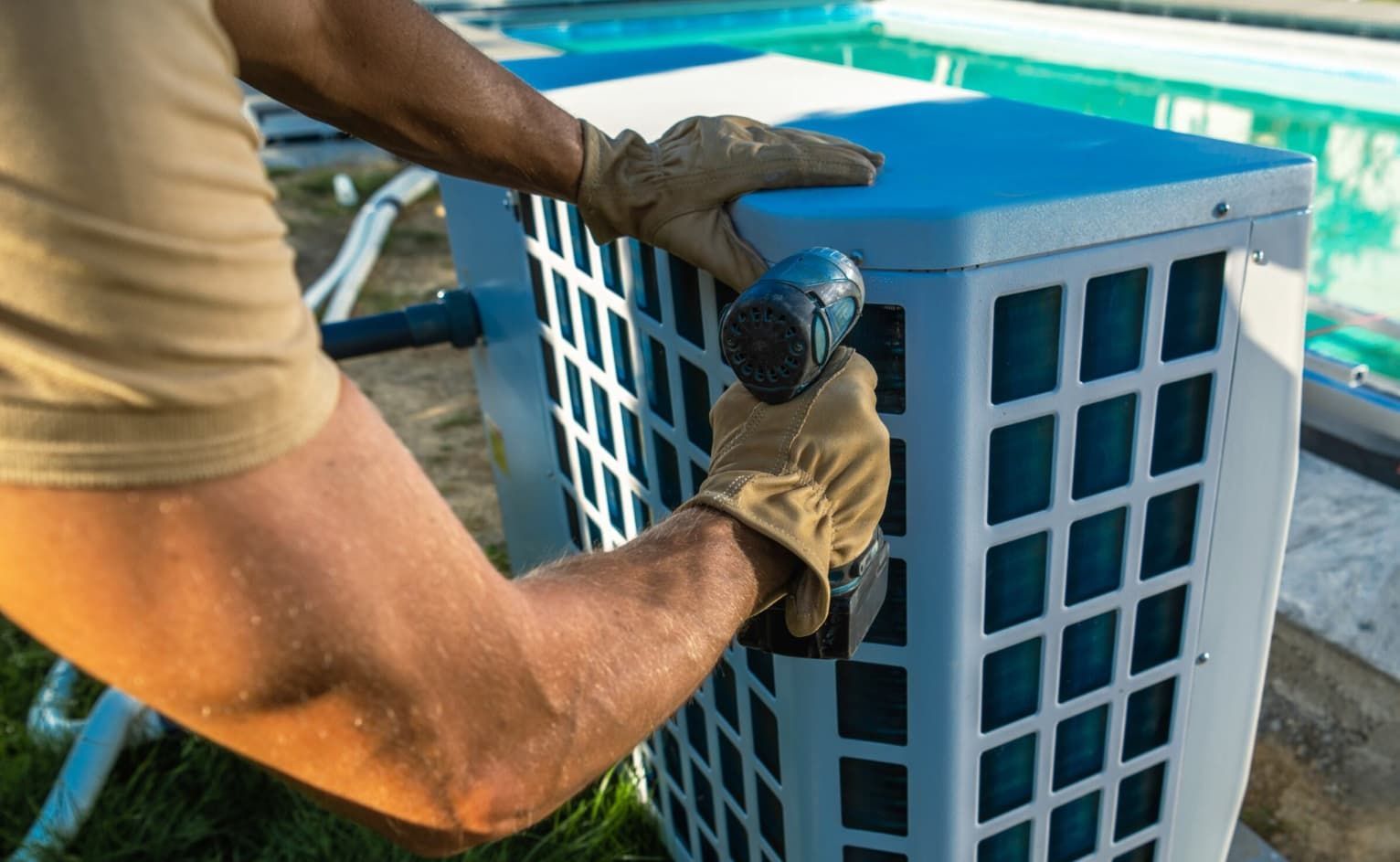 A Man Is Using A Drill To Fix An Air Conditioner Next To A Pool — Mozzlec Electrical & Airconditioning In Urangan, QLD