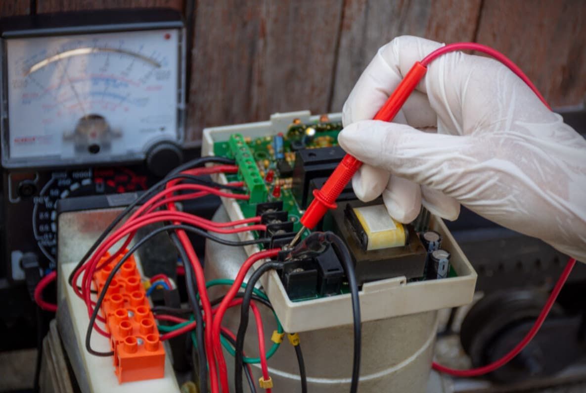 A Person Is Using A Multimeter To Test A Circuit Board — Mozzlec Electrical & Airconditioning In Urangan, QLD