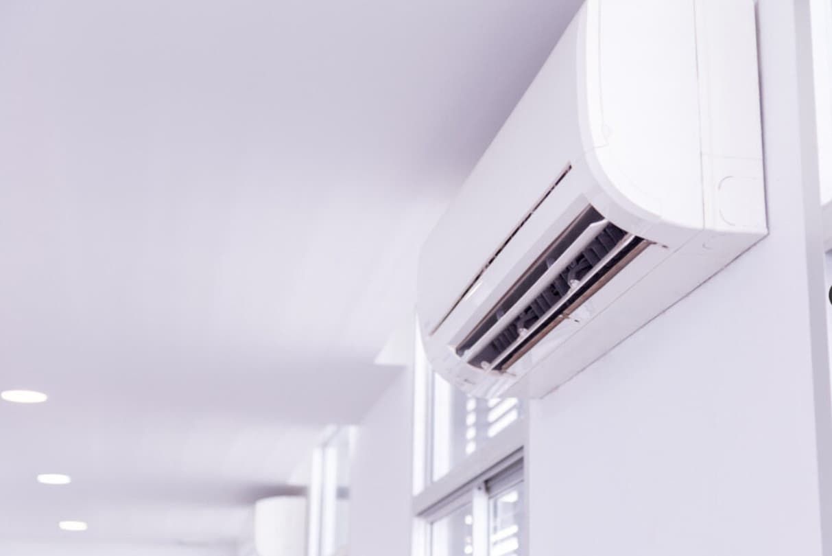 A White Air Conditioner Is Hanging On A White Wall In A Hallway — Mozzlec Electrical & Airconditioning In Urangan, QLD