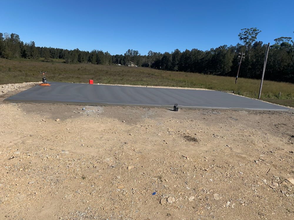 A Large Concrete Slab In The Middle Of A Dirt Field  — Brodie Wynter Concreting in Port Macquarie, NSW