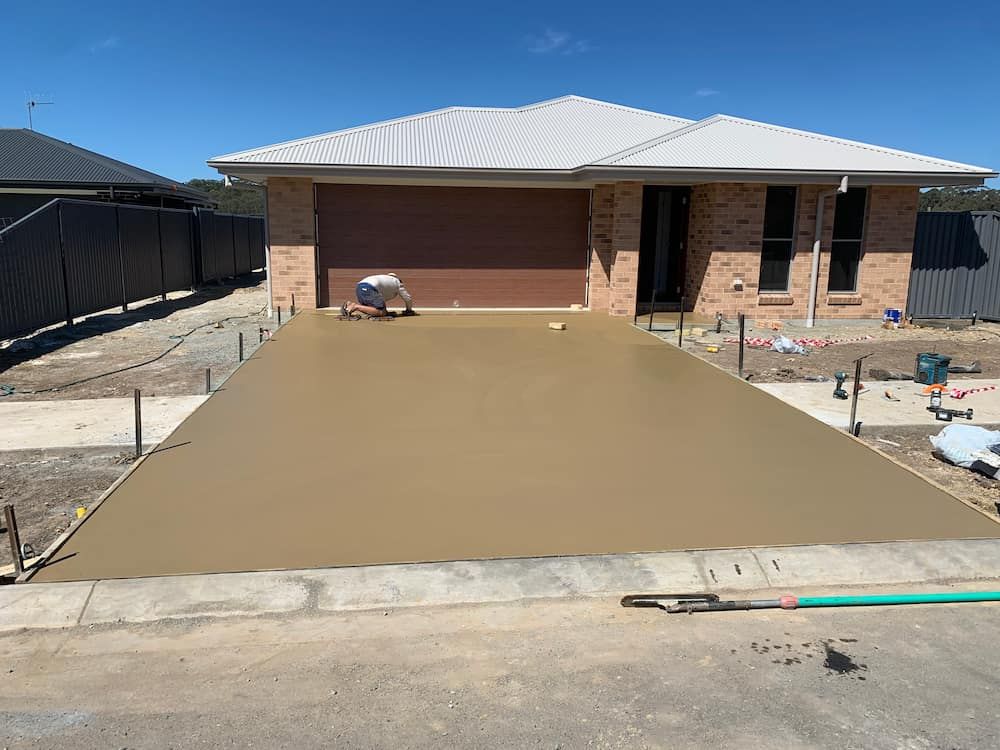 A Concrete Driveway Is Being Built In Front Of A Brick House  — Brodie Wynter Concreting in Macksville, NSW
