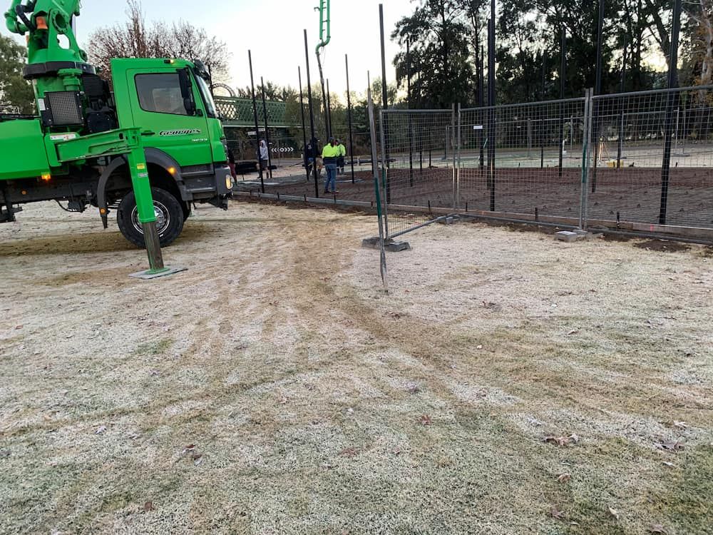 A Green Truck Is Driving Down A Dirt Road Next To A Fence  — Brodie Wynter Concreting in Port Macquarie, NSW
