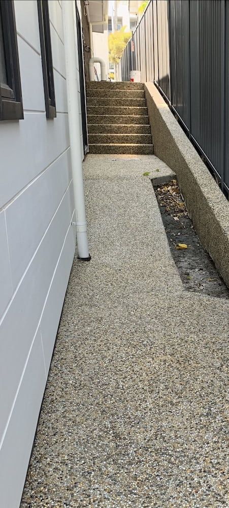 A Sidewalk Next To A House With Stairs Leading Up To It  — Brodie Wynter Concreting in Laurieton, NSW