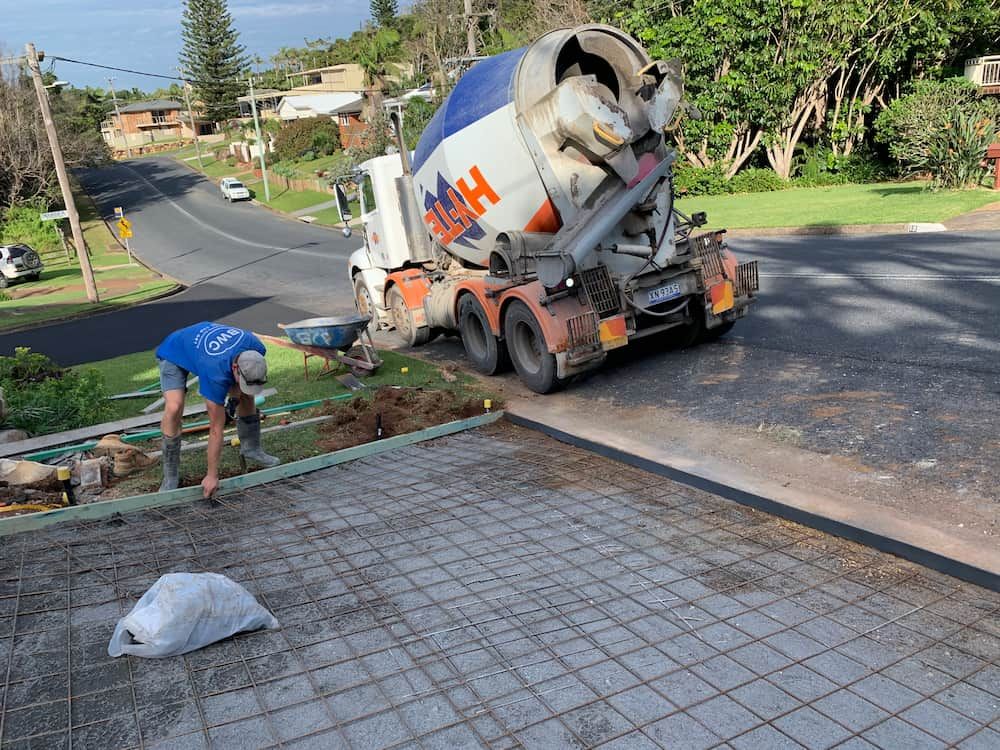 A Man Is Working On A Driveway Next To A Concrete Mixer Truck  — Brodie Wynter Concreting in Dubbo, NSW
