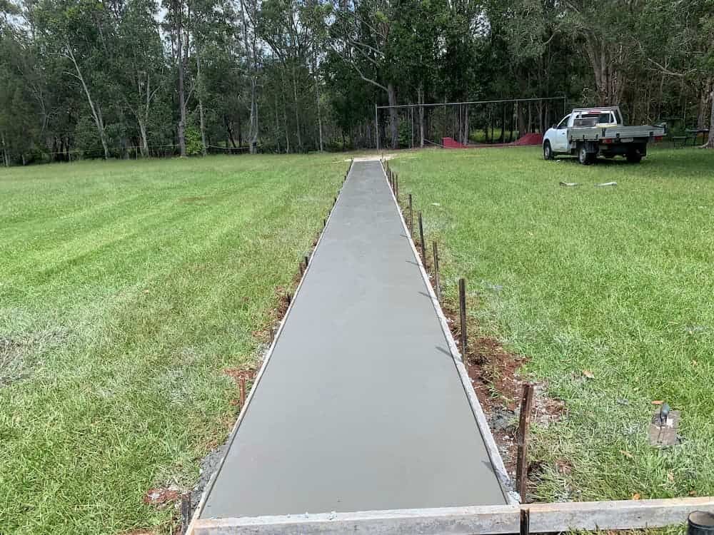 A Concrete Walkway Is Being Built In A Grassy Field  — Brodie Wynter Concreting in Harrington, NSW