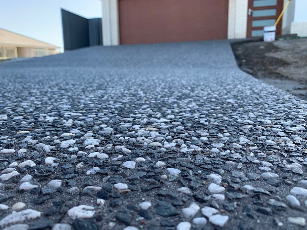A Close Up Of A Gravel Driveway In Front Of A Garage — Brodie Wynter Concreting in Coffs Harbour, NSW