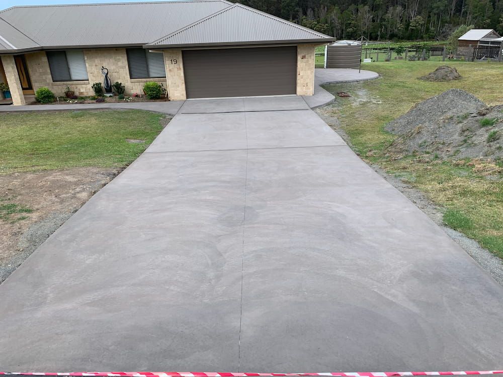 A Concrete Driveway Leading To A House With A Garage  — Brodie Wynter Concreting in Nambucca Heads, NSW