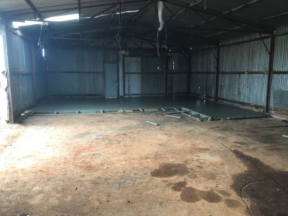 An Empty Warehouse With A Concrete Floor And A Metal Roof  — Brodie Wynter Concreting in Harrington, NSW