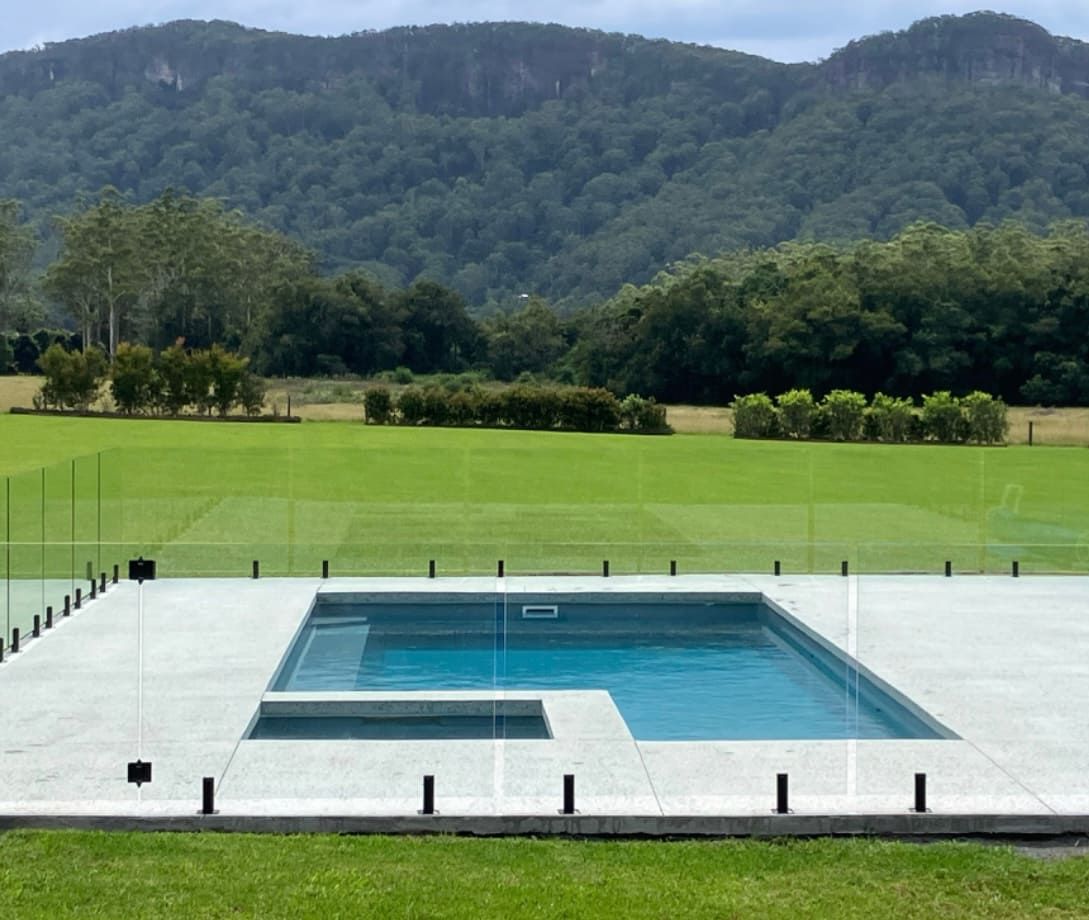 A Large Swimming Pool With Mountains In The Background — Brodie Wynter Concreting in Coffs Harbour, NSW